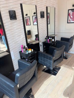une photo d'un salon de coiffure avec des fauteuils et des miroirs