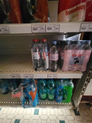 many bottles of water on the shelves in the store
