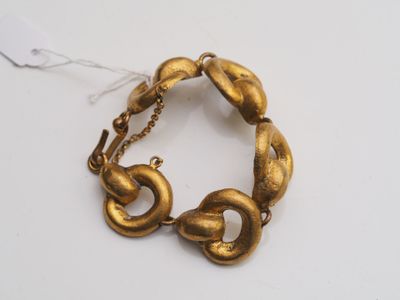 a close up of a gold bracelet on a white surface