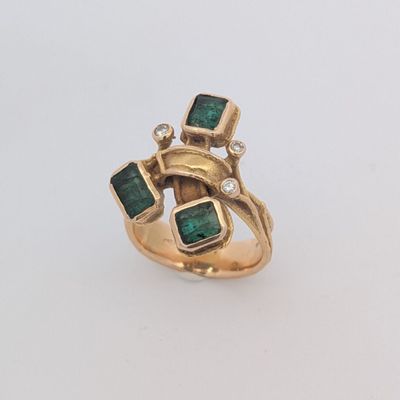 Gros plan sur une bague en or ornée d'émeraudes et de diamants