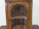 a small wooden cabinet with a glass door on top of it