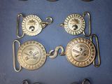 four silver metal buckles with a skull and crossbone on them