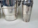 a silver ice bucket and a silver shaker on a white table