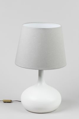 une lampe de table blanche surmontée d'un abat-jour gris