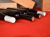several bottles of wine are lined up on a red table cloth