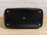 black leather toilet bag on a wooden table with a white brick wall in the background