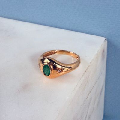 gros plan d'une bague en or avec une pierre verte