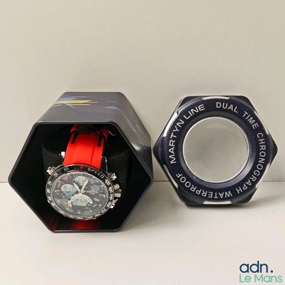 une montre dans un coffret noir avec un bracelet rouge