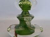 a green glass vase with a green lid on a white table