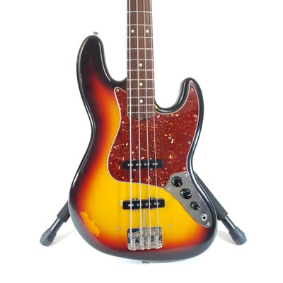 an electric bass guitar sitting on top of a stand on a white surface