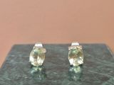 une paire de boucles d'oreilles à clous en saphir jaune posées sur une surface en marbre vert
