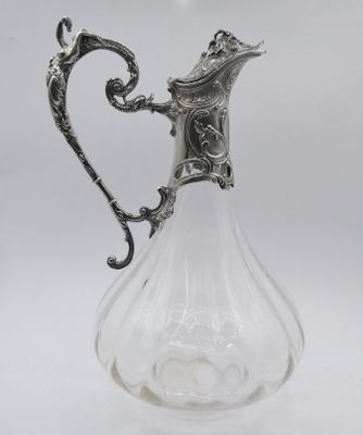 an antique silver plated glass pitcher with a floral design on the handle