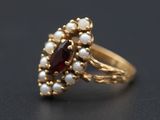 un gros plan d'une bague en or sertie de perles et de grenats