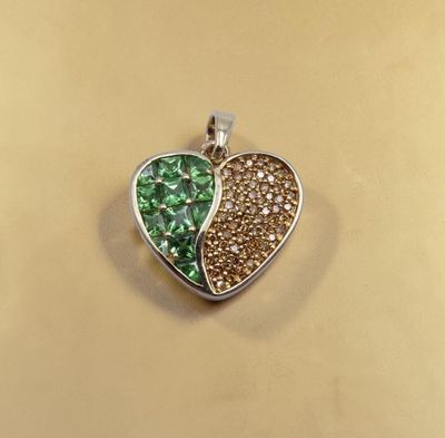 un pendentif en forme de cœur orné de cristaux verts et blancs sur fond doré