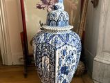 un vase bleu et blanc posé par terre à côté d'une photo encadrée
