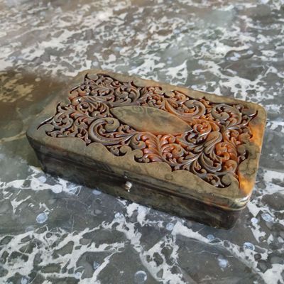 une petite boîte en bois ornée de sculptures, posée sur une table