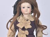 a doll that is wearing a purple dress and a hat