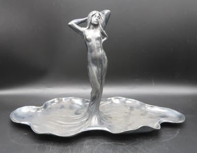 a silver statue of a woman standing on a plate