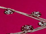 three necklaces with charms on a chain on a pink surface
