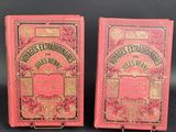 two old books are sitting side by side on a black surface