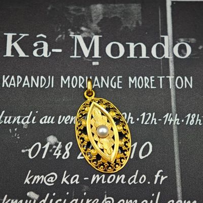 un pendentif en or orné d'une perle, posé sur une plaque