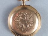 an image of a gold pocket watch on a blue surface
