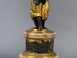 an image of a statue of a man holding a bowl on a pedestal