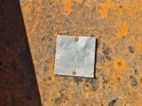 une plaque métallique posée sur une surface rouillée