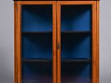 a wooden cabinet with blue glass doors and two shelves