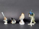 three figurines of birds and a woman with a bird on a branch