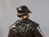 a bronze statue of a man with a hat and coat