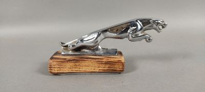 une statue en argent représentant un chien, posée sur un socle en bois