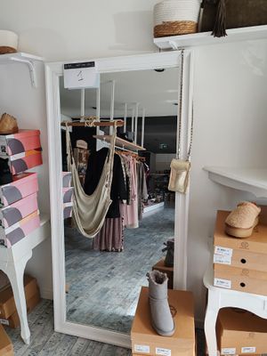 a mirror in the corner of a room that has clothes on hangers