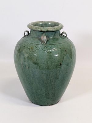 un vase vert posé sur une surface blanche