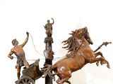 bronze statue of a chariot pulled by two horses and a man on a cart