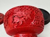 a red vase sitting on a table with a lid