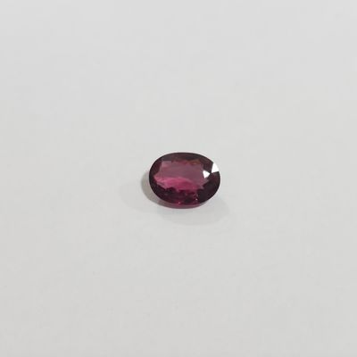 Gros plan sur une tourmaline rose posée sur une surface blanche