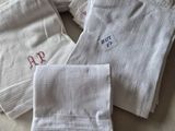 three white towels with embroidered monograms on them on a bed