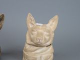 two ceramic figurines of dogs sitting next to each other on a gray surface
