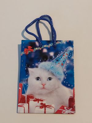 un chat blanc coiffé d'un chapeau de fête, posé sur un sac-cadeau