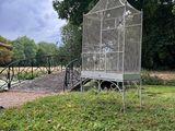 a bird cage sitting on top of a bench in a park