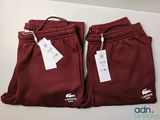 deux paires de pantalons de survêtement rouges, encore étiquetés, posées sur une table
