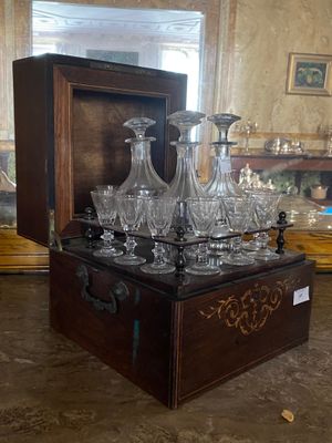 bottles and glasses in a wooden box on a table in a room