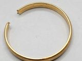 a close up of a gold bracelet on a white surface