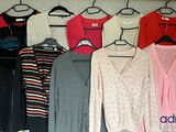 a lot of sweaters hanging on a rack in a closet