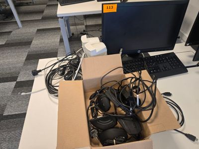 une boîte remplie d'écouteurs et un ordinateur posé sur un bureau