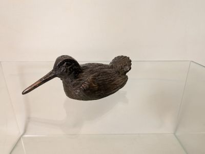 statue of a bird in a glass display case on a white wall