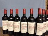 six bottles of red wine lined up in a row on a table