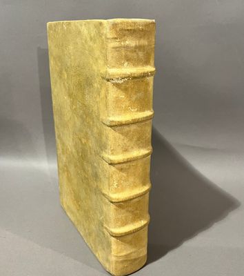 un vieux livre jaune posé sur une table près d'un mur gris