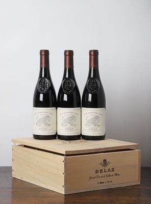 trois bouteilles de vin rouge dans une caisse en bois posée sur une table